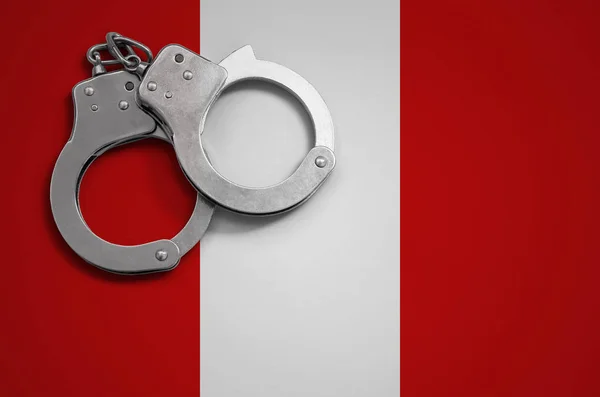 Peru flag  and police handcuffs. The concept of crime and offenses in the country.
