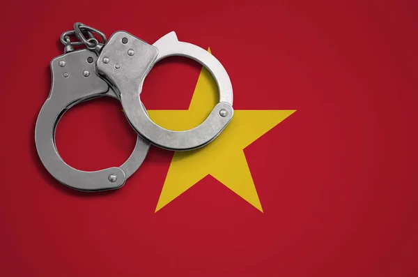 Vietnam flag  and police handcuffs. The concept of crime and offenses in the country.