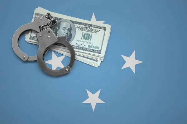 Micronesia flag  with handcuffs and a bundle of dollars. The concept of breaking the law and thieves crimes.