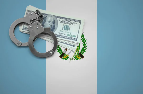 Guatemala flag  with handcuffs and a bundle of dollars. The concept of breaking the law and thieves crimes.