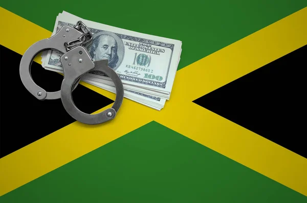 Jamaica flag  with handcuffs and a bundle of dollars. The concept of breaking the law and thieves crimes.