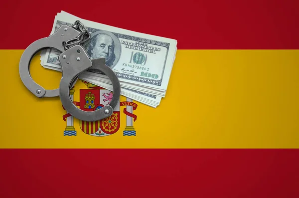 Spain flag  with handcuffs and a bundle of dollars. The concept of breaking the law and thieves crimes.