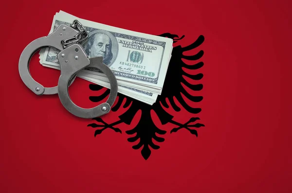 Albania flag  with handcuffs and a bundle of dollars. The concept of breaking the law and thieves crimes.