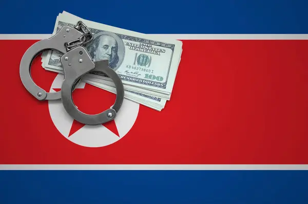 North Korea flag  with handcuffs and a bundle of dollars. The concept of breaking the law and thieves crimes.