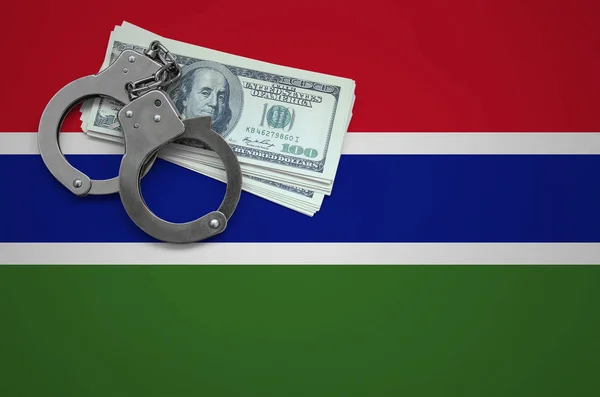 Gambia flag  with handcuffs and a bundle of dollars. The concept of breaking the law and thieves crimes.