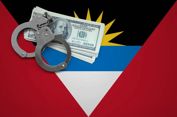 Antigua and Barbuda flag  with handcuffs and a bundle of dollars. The concept of breaking the law and thieves crimes.