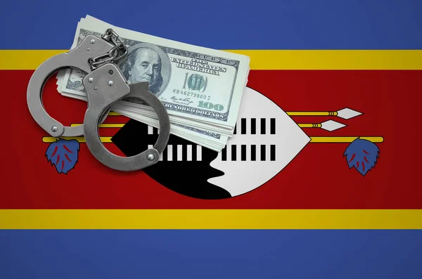 Swaziland flag  with handcuffs and a bundle of dollars. The concept of breaking the law and thieves crimes.