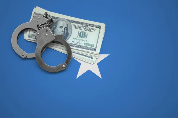 Somalia flag  with handcuffs and a bundle of dollars. The concept of breaking the law and thieves crimes.