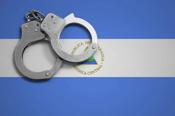 Nicaragua flag  and police handcuffs. The concept of crime and offenses in the country.