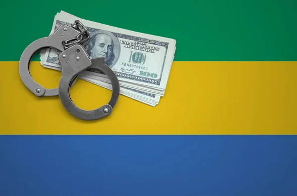 Gabon flag  with handcuffs and a bundle of dollars. The concept of breaking the law and thieves crimes.