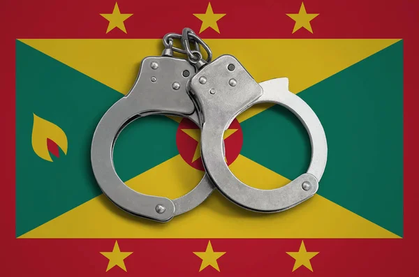 Grenada flag  and police handcuffs. The concept of observance of the law in the country and protection from crime.