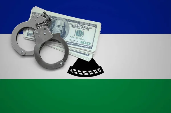 Lesotho flag  with handcuffs and a bundle of dollars. The concept of breaking the law and thieves crimes.