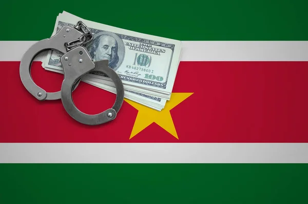 Suriname flag  with handcuffs and a bundle of dollars. The concept of breaking the law and thieves crimes.