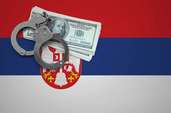 Serbia flag  with handcuffs and a bundle of dollars. The concept of breaking the law and thieves crimes.
