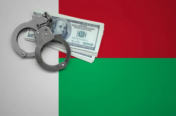 Madagascar flag  with handcuffs and a bundle of dollars. The concept of breaking the law and thieves crimes.