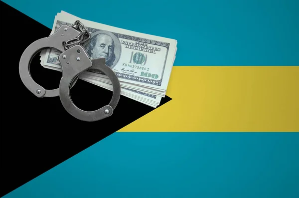 Bahamas flag  with handcuffs and a bundle of dollars. The concept of breaking the law and thieves crimes.