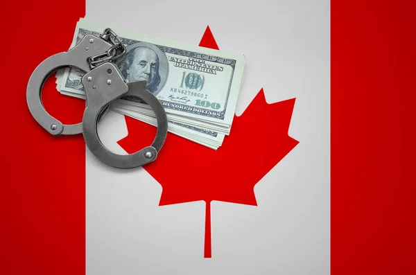 Canada flag  with handcuffs and a bundle of dollars. The concept of breaking the law and thieves crimes.