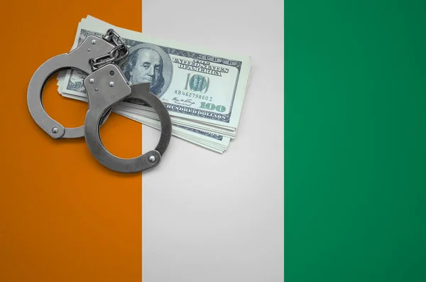 Ivory Coast flag  with handcuffs and a bundle of dollars. The concept of breaking the law and thieves crimes.