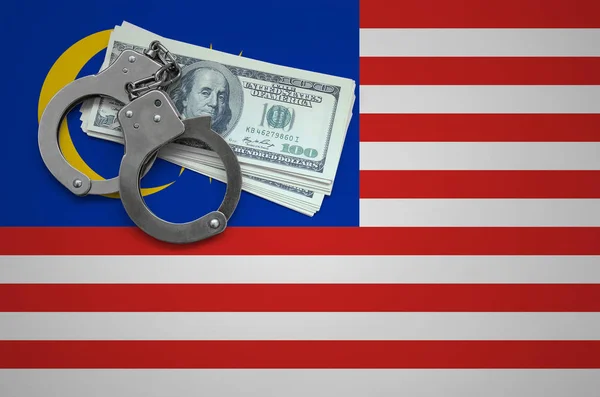 Malaysia flag  with handcuffs and a bundle of dollars. The concept of breaking the law and thieves crimes.