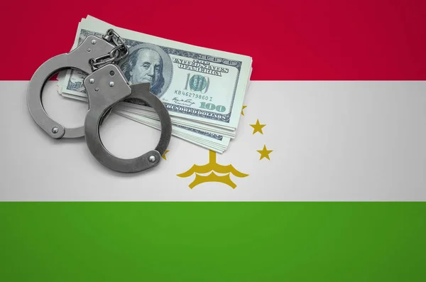 Tajikistan flag  with handcuffs and a bundle of dollars. The concept of breaking the law and thieves crimes.