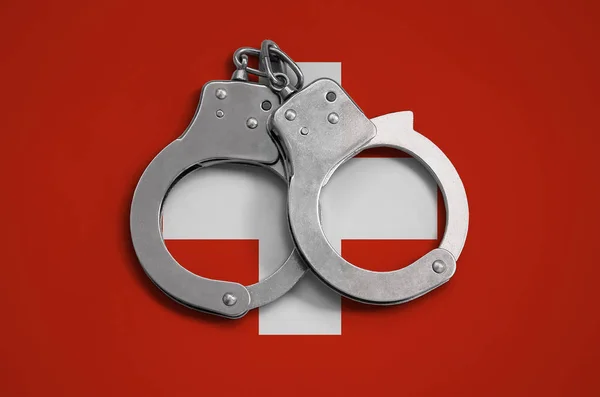 Switzerland flag  and police handcuffs. The concept of observance of the law in the country and protection from crime.