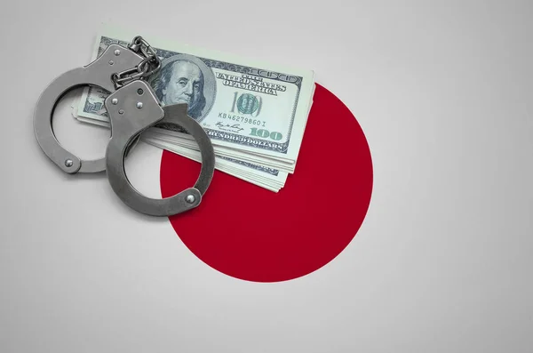 Japan flag  with handcuffs and a bundle of dollars. The concept of breaking the law and thieves crimes.