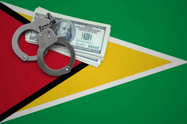Guyana flag  with handcuffs and a bundle of dollars. The concept of breaking the law and thieves crimes.