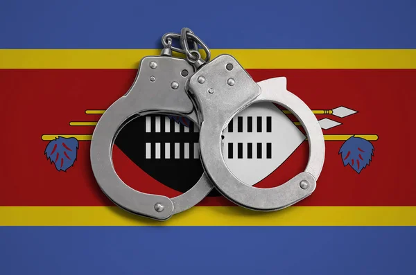 Swaziland flag  and police handcuffs. The concept of observance of the law in the country and protection from crime.
