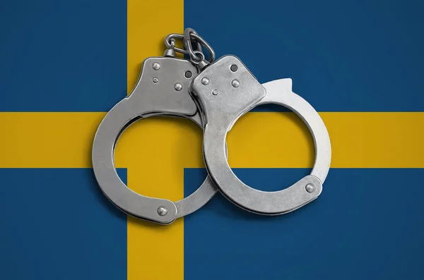 Sweden flag  and police handcuffs. The concept of observance of the law in the country and protection from crime.