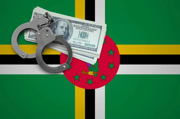 Dominica flag  with handcuffs and a bundle of dollars. The concept of breaking the law and thieves crimes.