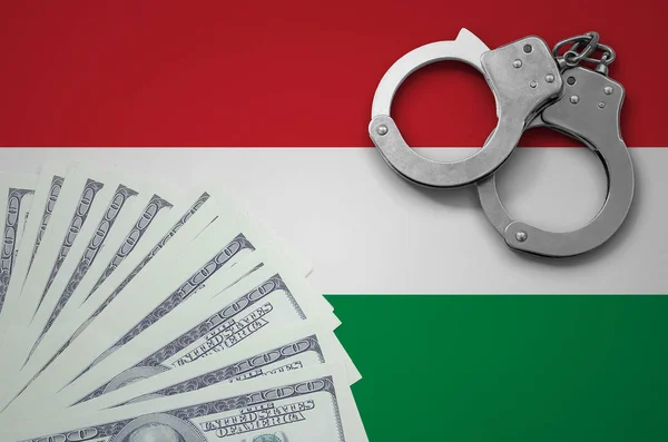 Hungary flag  with handcuffs and a bundle of dollars. The concept of illegal banking operations in US currency.