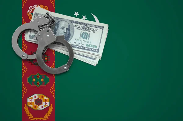 Turkmenistan flag  with handcuffs and a bundle of dollars. The concept of breaking the law and thieves crimes.