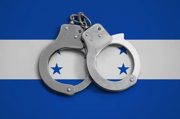 Honduras flag  and police handcuffs. The concept of observance of the law in the country and protection from crime.