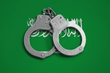 Suudi Arabistan bayrağı ve polis kelepçe. Ülke ve suç karşı koruma kanununda gözetilmesi kavramı.