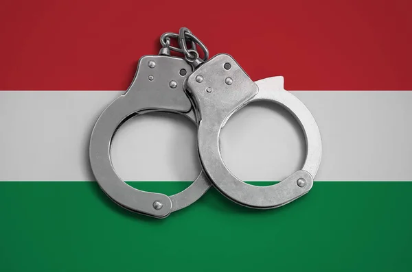 Hungary flag  and police handcuffs. The concept of observance of the law in the country and protection from crime.
