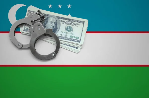 Uzbekistan flag  with handcuffs and a bundle of dollars. The concept of breaking the law and thieves crimes.