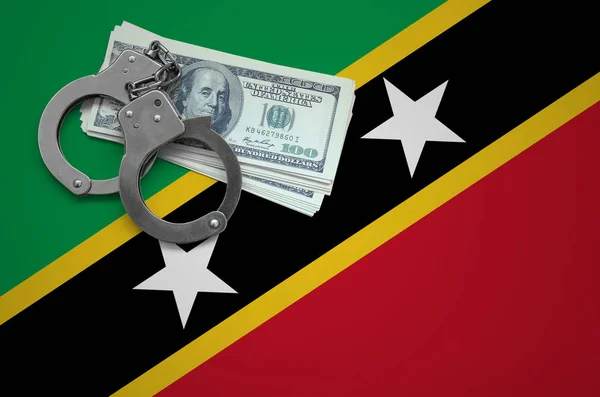 Saint Kitts and Nevis flag  with handcuffs and a bundle of dollars. The concept of breaking the law and thieves crimes.
