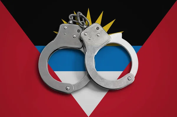 Antigua and Barbuda flag  and police handcuffs. The concept of observance of the law in the country and protection from crime.