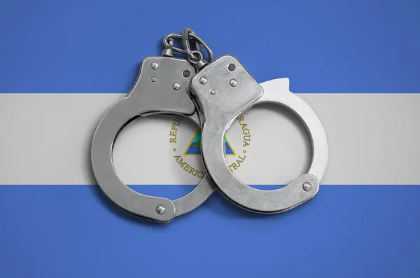 Nicaragua flag  and police handcuffs. The concept of observance of the law in the country and protection from crime.