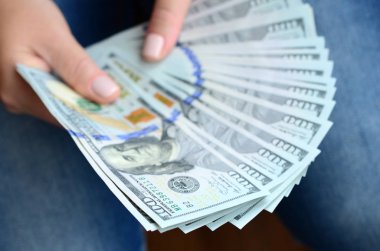 A yelpaze-in yüz dolar Bono tutan bir kız.
