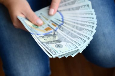 A yelpaze-in yüz dolar Bono tutan bir kız.