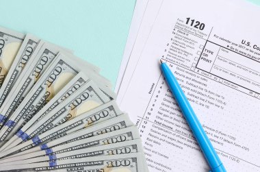 1120 formu yalan yüz dolar faturaları ve ışık mavi zemin üzerine mavi kalem yakın vergi. Bize gelir vergisi iade Corporation.