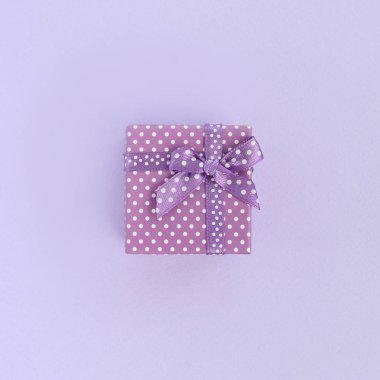 Küçük mor hediye kutusu kurdele ile mor bir arka plan üzerinde yatıyor. Üstten görünüm minimalizm düz yatıyordu.
