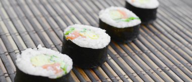 Suşi yalan bir bambu hasır serwing mindere alır. Geleneksel Asya gıda.