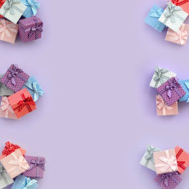 Küçük renkli hediye kutuları şeritler yığınları mor bir arka plan üzerinde yatıyor. Üstten görünüm desen minimalizm düz yatıyordu.