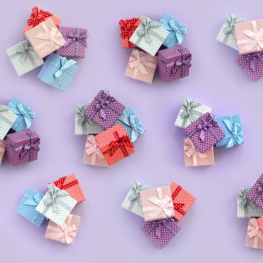 Küçük renkli hediye kutuları şeritler yığınları mor bir arka plan üzerinde yatıyor. Üstten görünüm desen minimalizm düz yatıyordu.