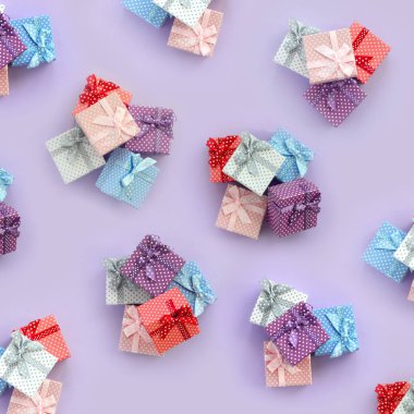 Küçük renkli hediye kutuları şeritler yığınları mor bir arka plan üzerinde yatıyor. Üstten görünüm desen minimalizm düz yatıyordu.