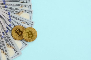 Altın bitcoins ve açık mavi renkli üzerinde yüz dolar faturaları yalan.
