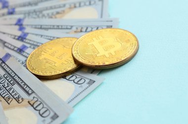 Altın bitcoins ve açık mavi renkli üzerinde yüz dolar faturaları yalan.