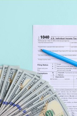 1040 formu yalan yüz dolar faturaları ve ışık mavi zemin üzerine mavi kalem yakın vergi. Bize bireysel gelir vergisi beyannamesi.
